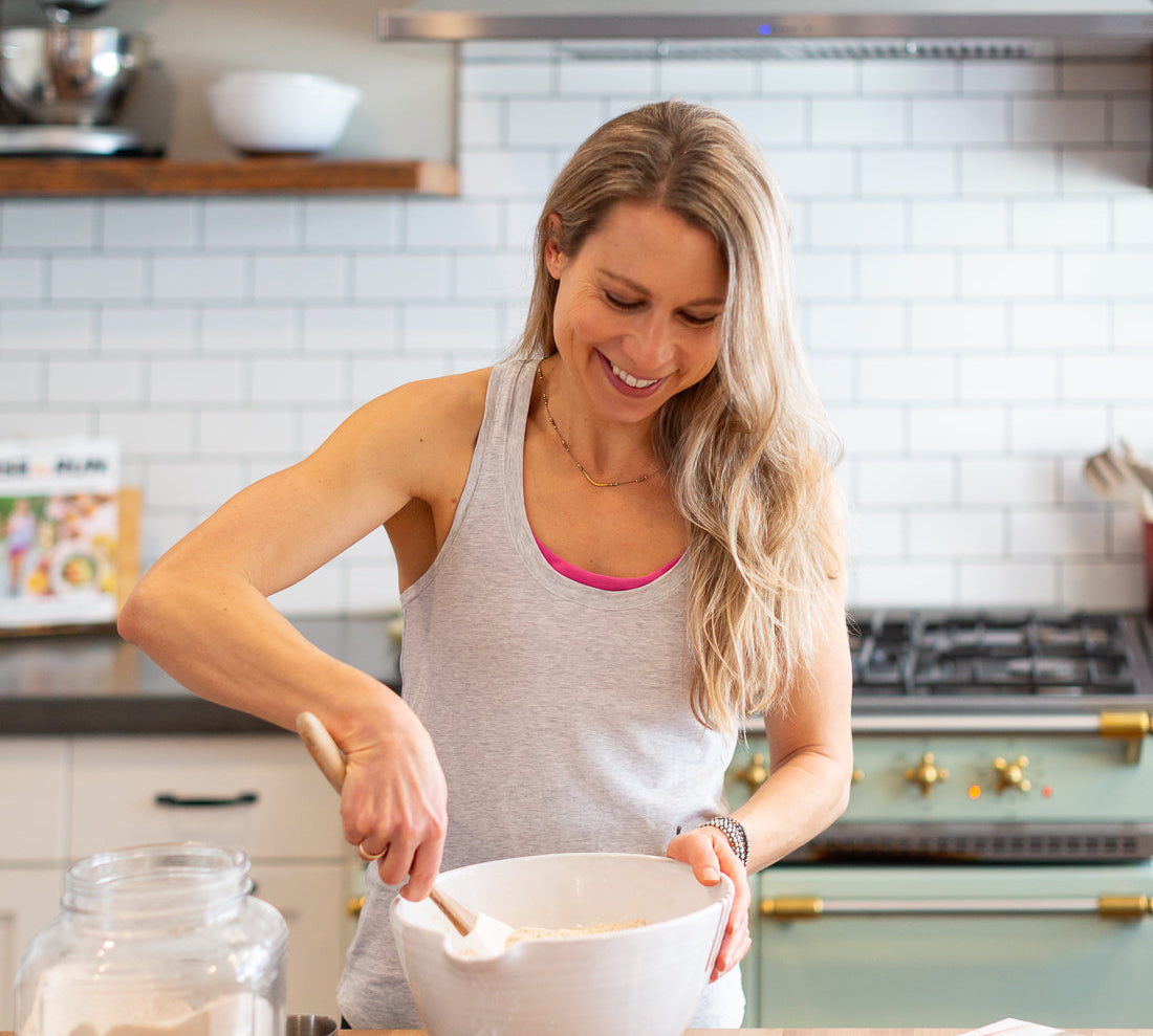 Vertical photo of Run Fast Eat Slow Superhero Muffins Founder Elyse Kopecky mixing muffins in her kitchen