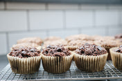 Chocolate Banana Superhero Muffins on a cooling rack with a tiled wall background.