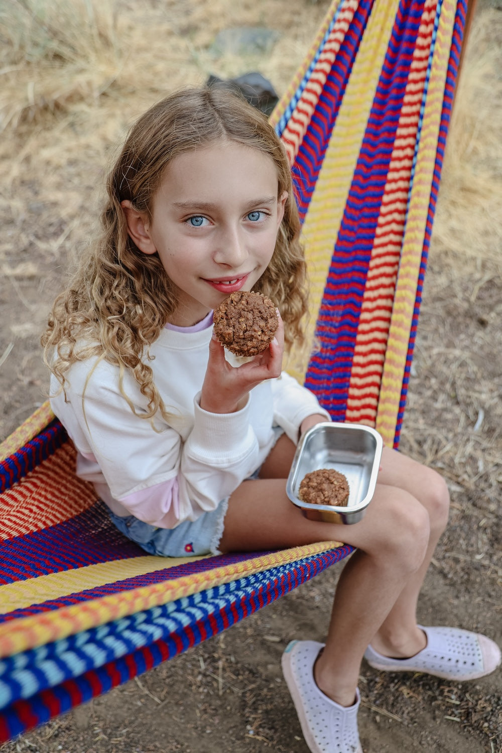 Young girl on a hammock eating a Superhero Muffin